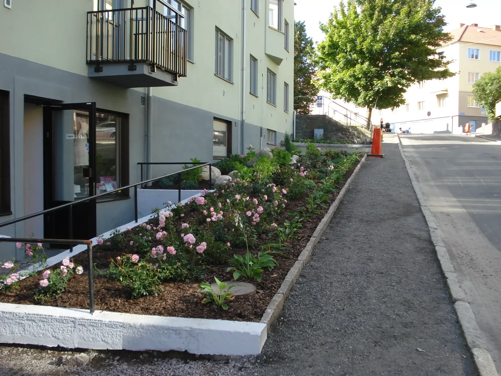 Rabatt med blommor längs gångbanan vid fasaden