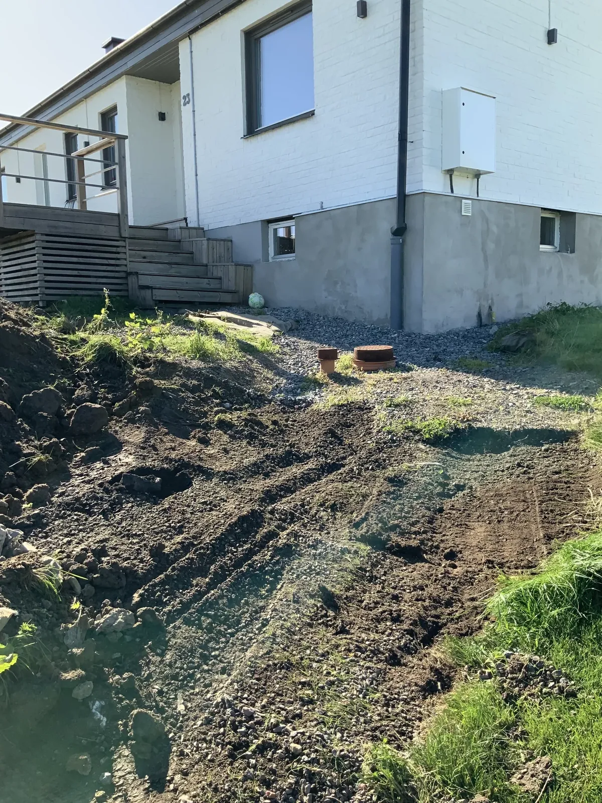 Uppgrävd slänt vid ett vitt hus innan arbetet