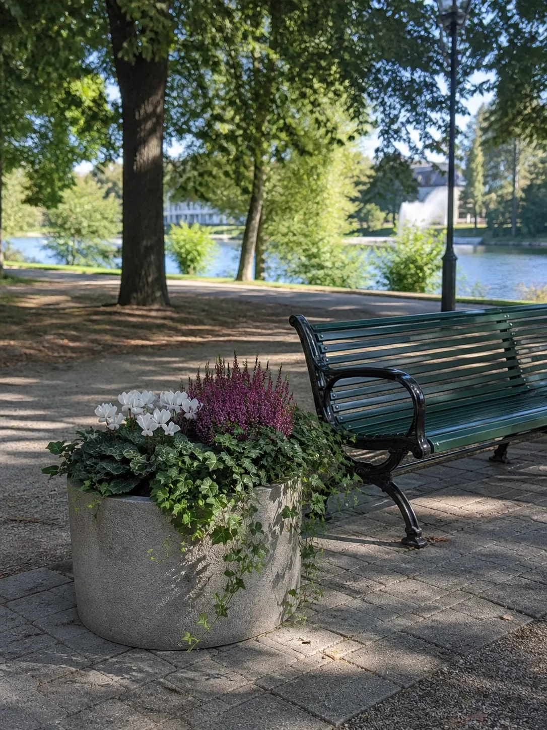 Planteringskruka med vita och lila blommor vid en parkbänk