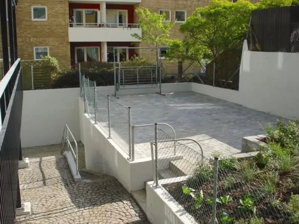 Stenlagd innergård med nya planteringar vid ett flerbostadshus