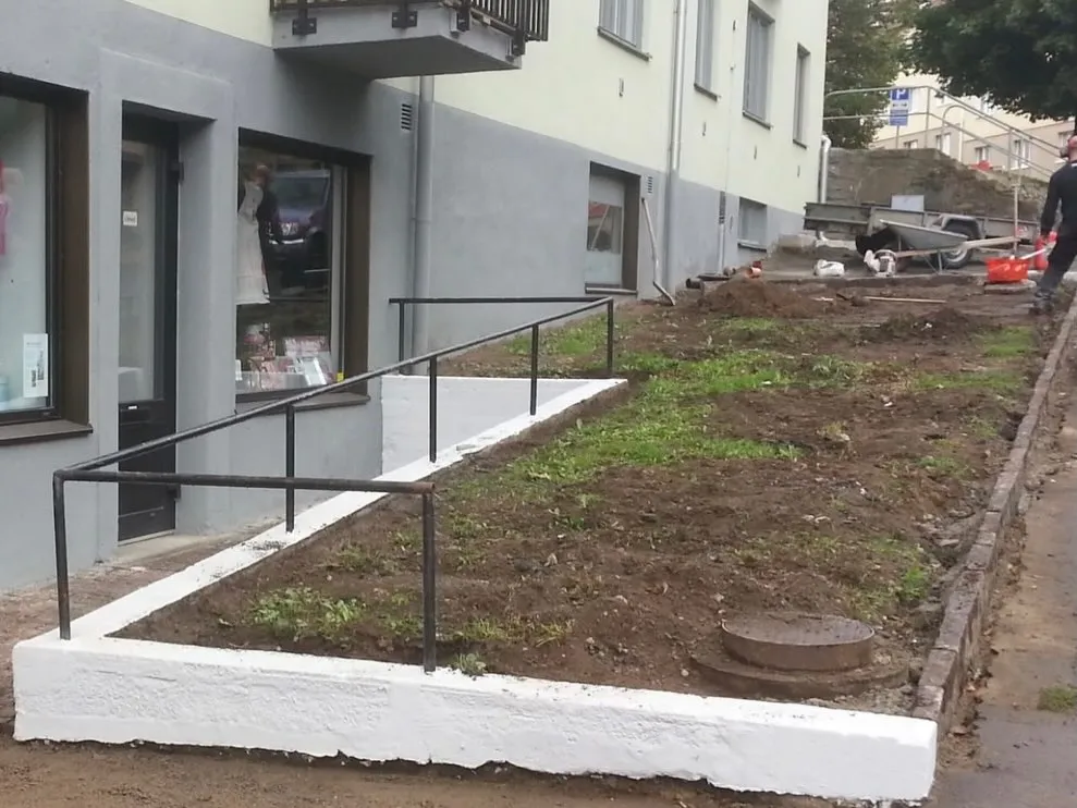 Ny jord och vit kantsten under arbetet vid ett flerbostadshus