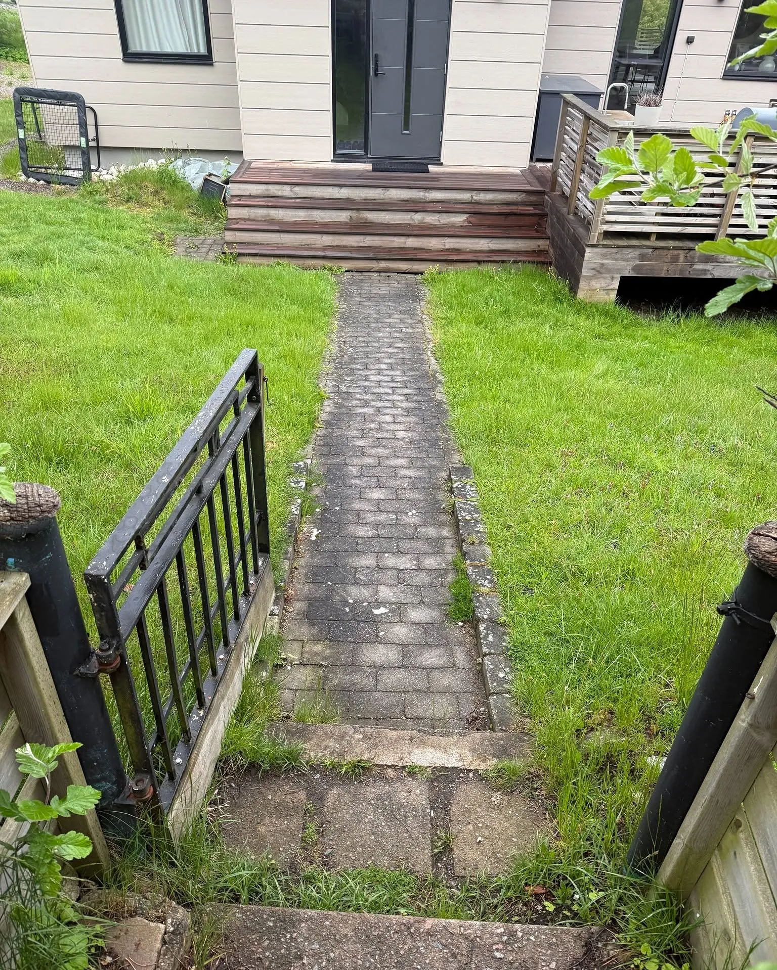 Stengång genom gräsmattan ner mot en trappa vid ett hus