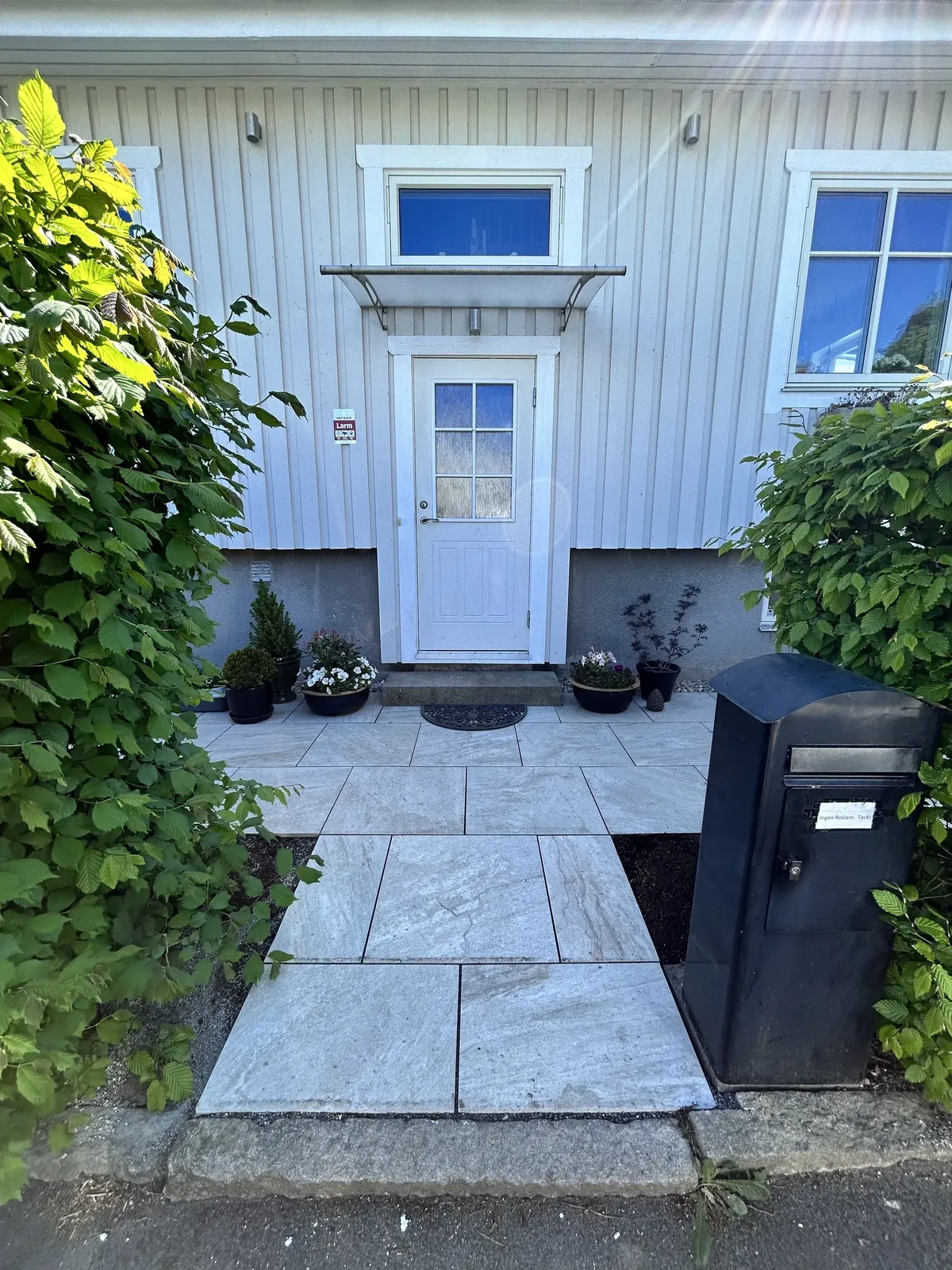 Ny stenläggning vid entrén till ett vitt trähus