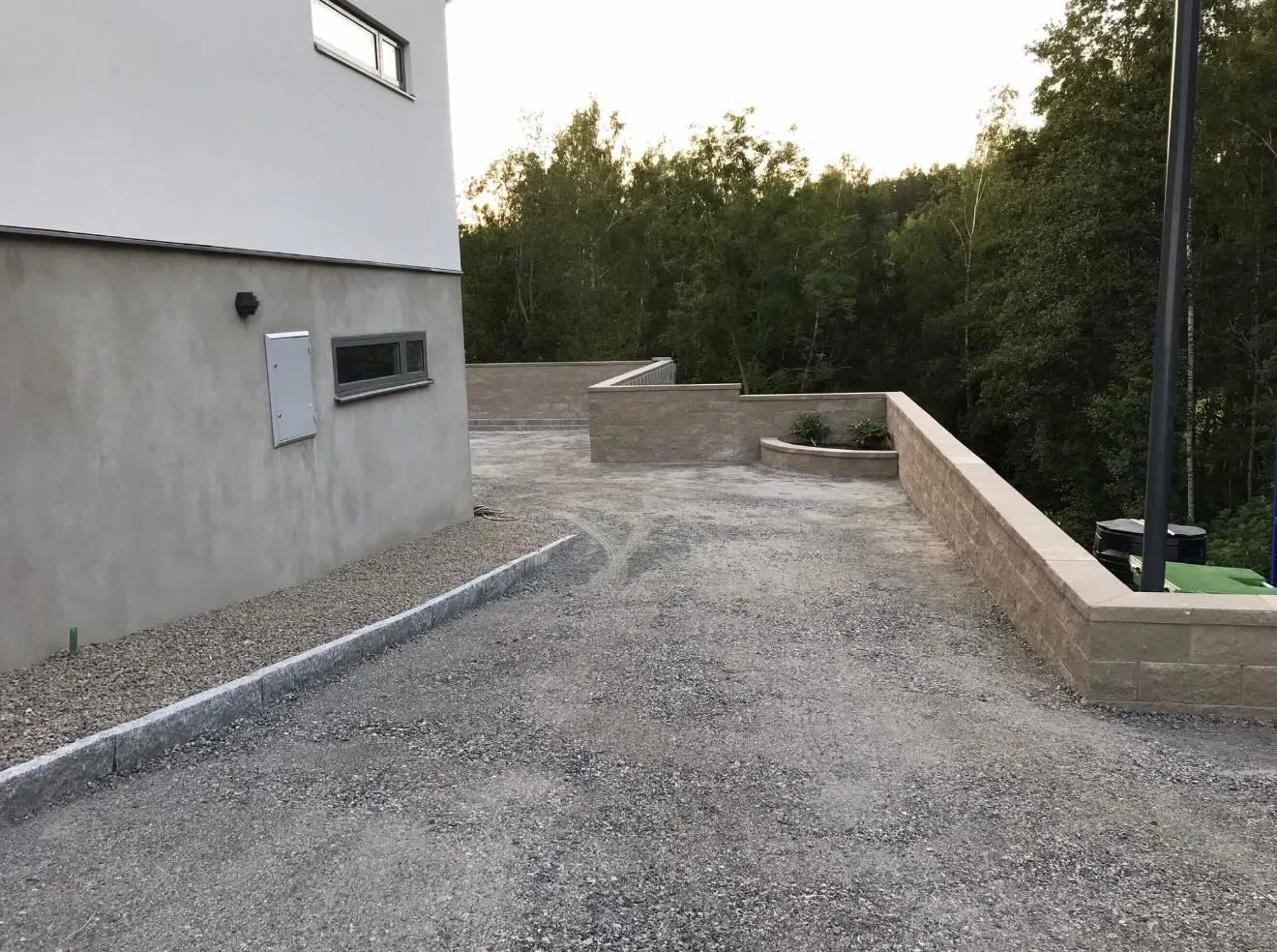 Nybyggd mur och kantsten längs en husvägg