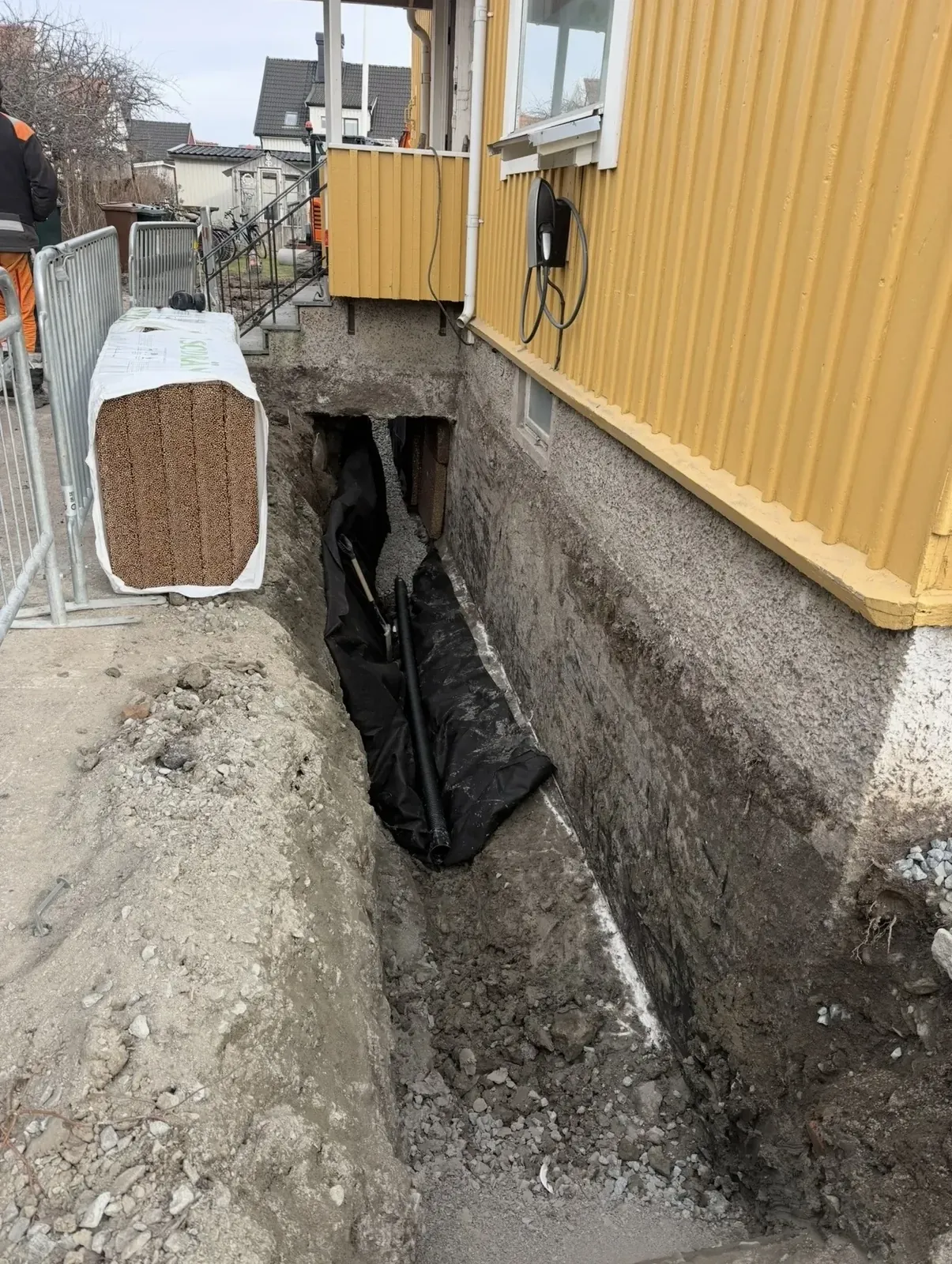 Schakt längs husgrunden med svart fuktskyddsmatta