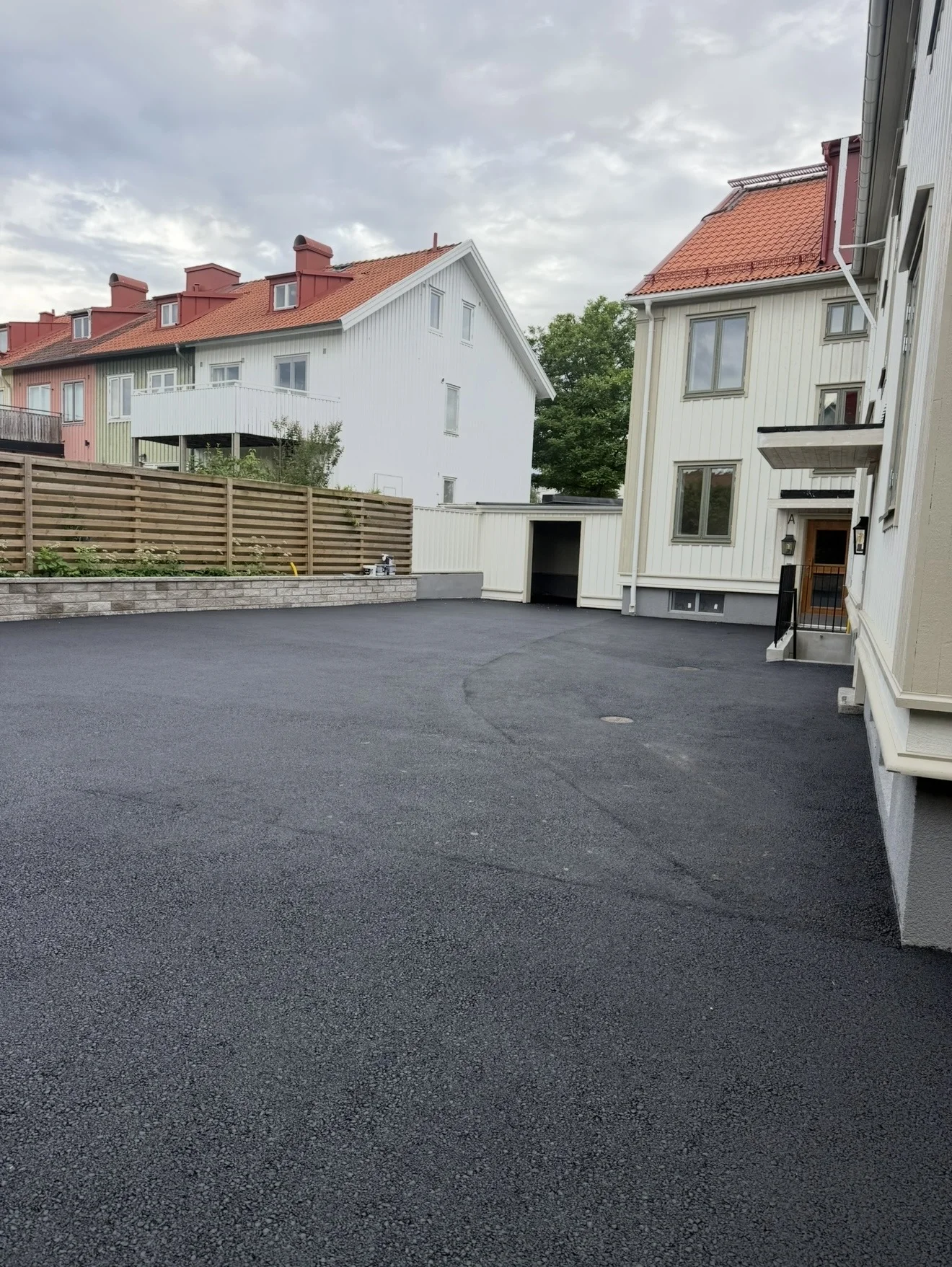 Nyasfalterad gårdsplan vid ljusa flerbostadshus