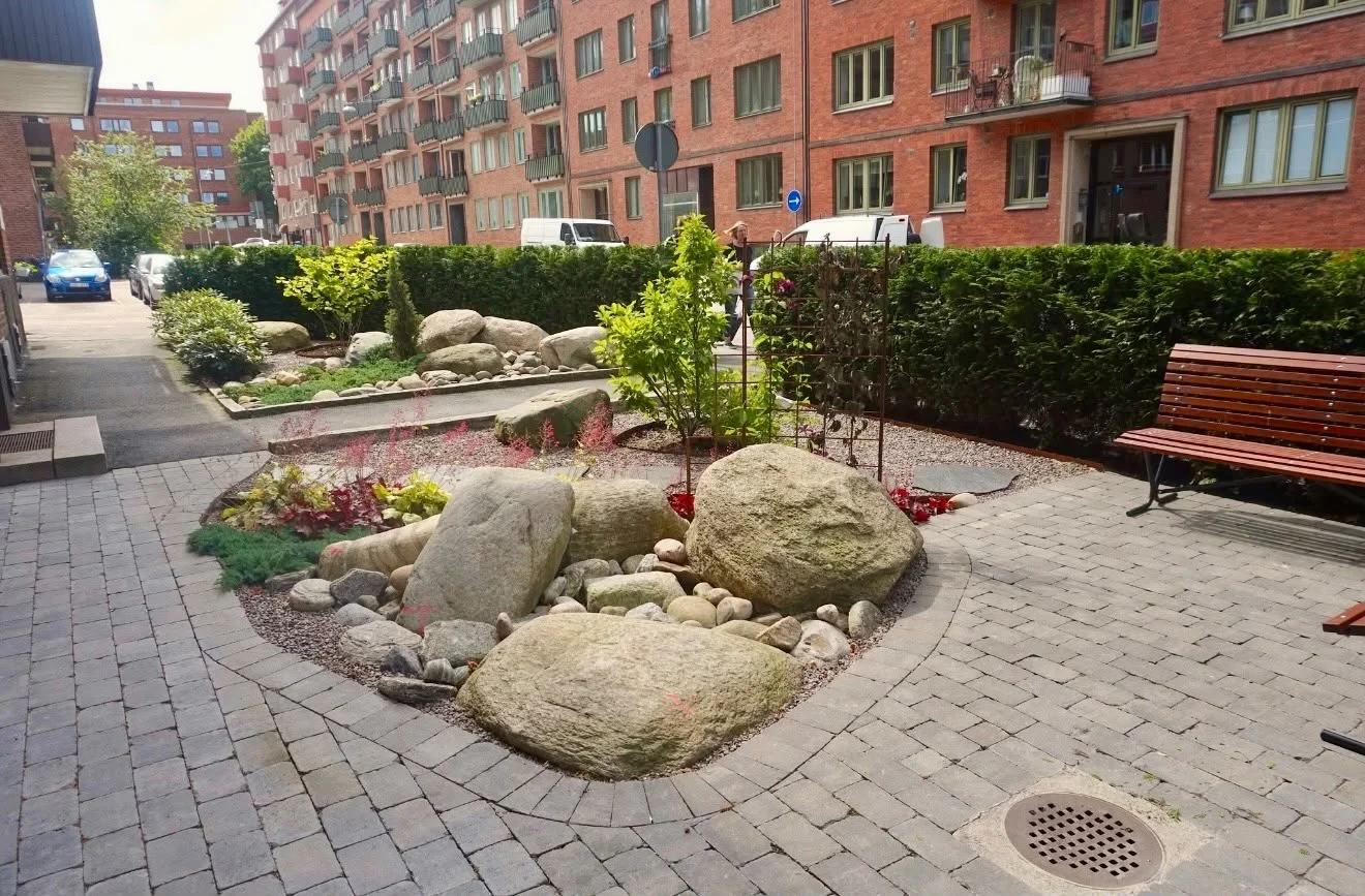 Rund stenlagd yta med naturstenar och planteringar