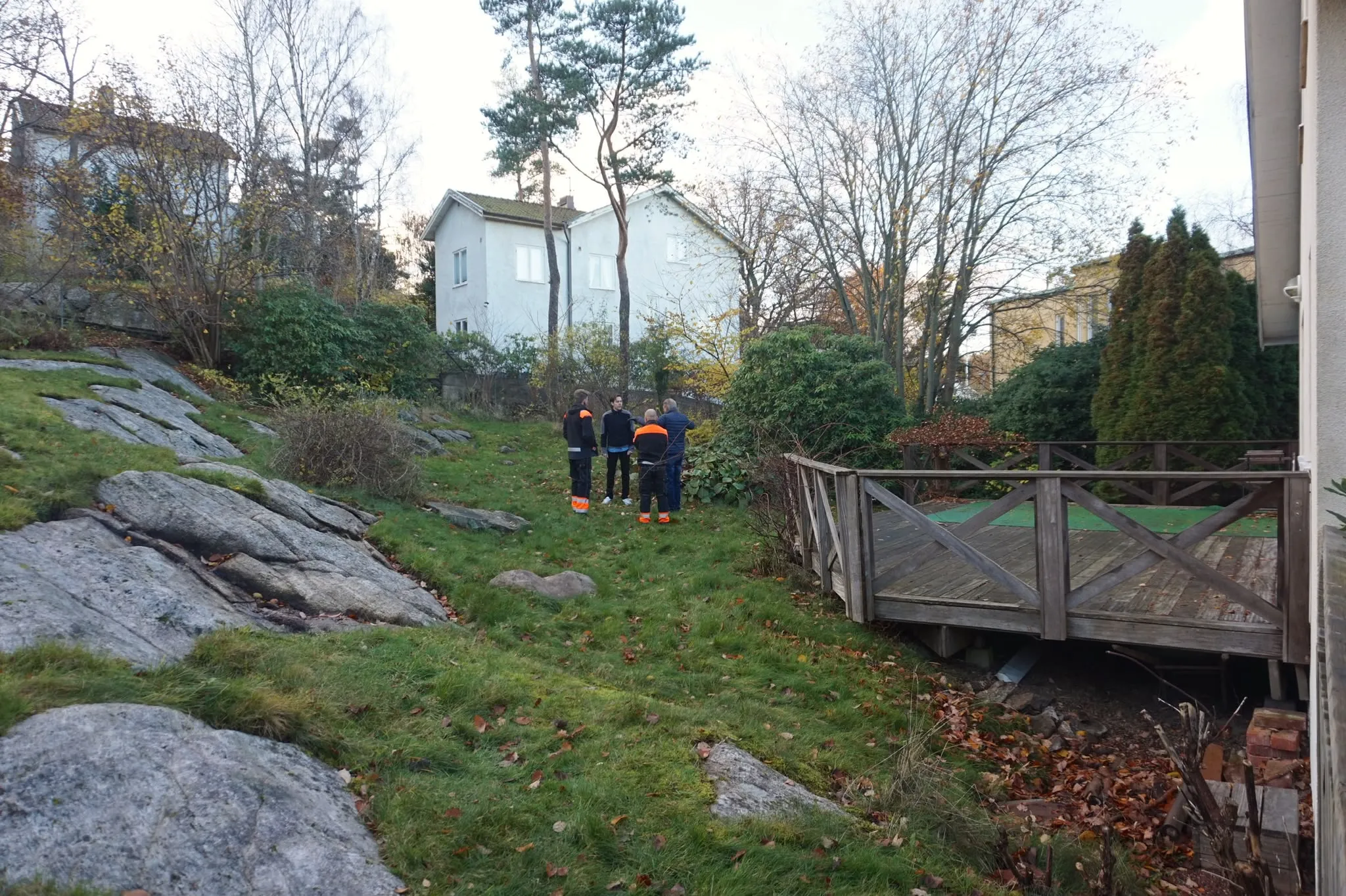 Kuperad tomt med berg och träräcke innan arbetet