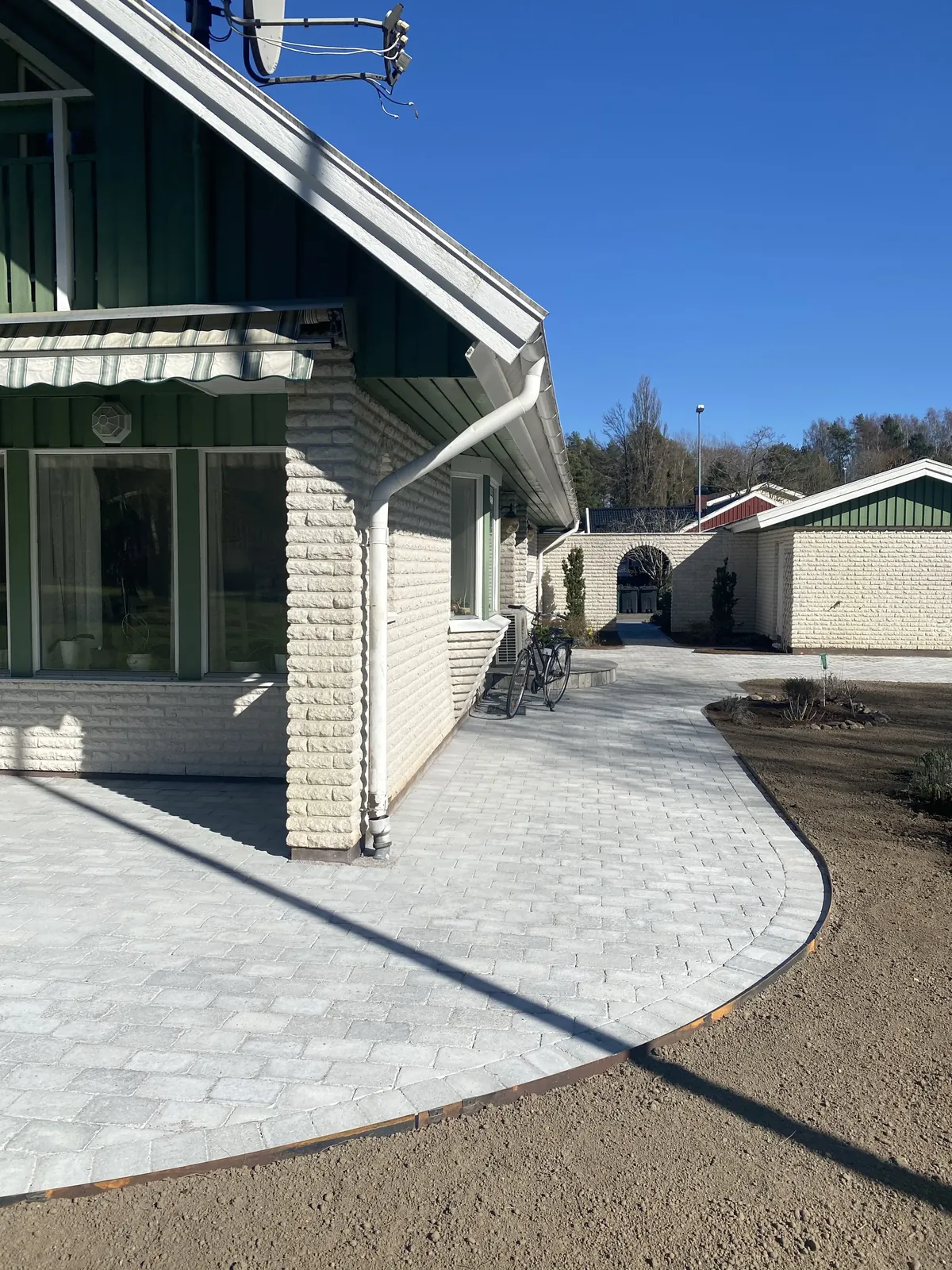 Ny stenläggning runt huset med rundade kanter
