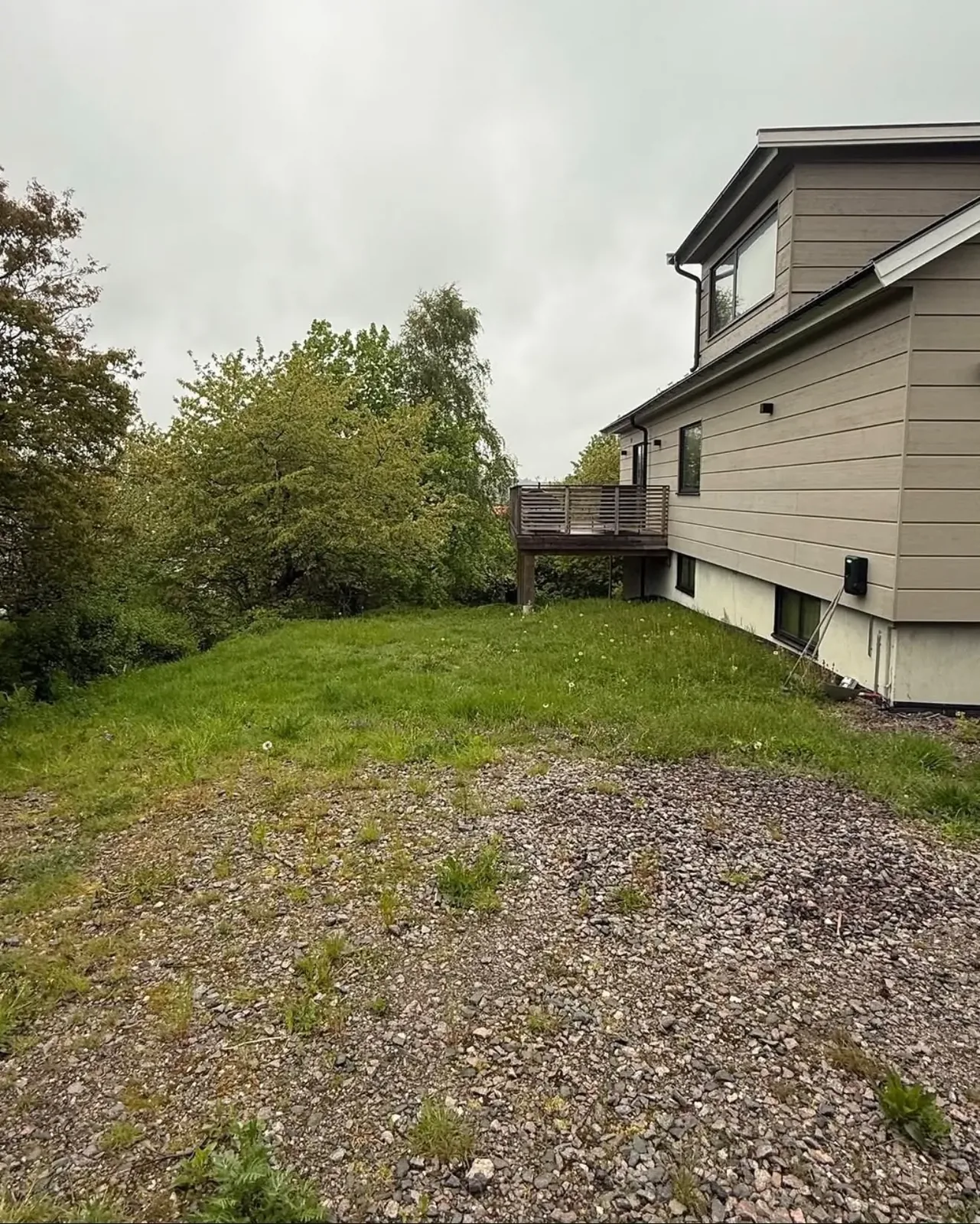 Ojämn grusyta vid ett beige hus innan arbetet