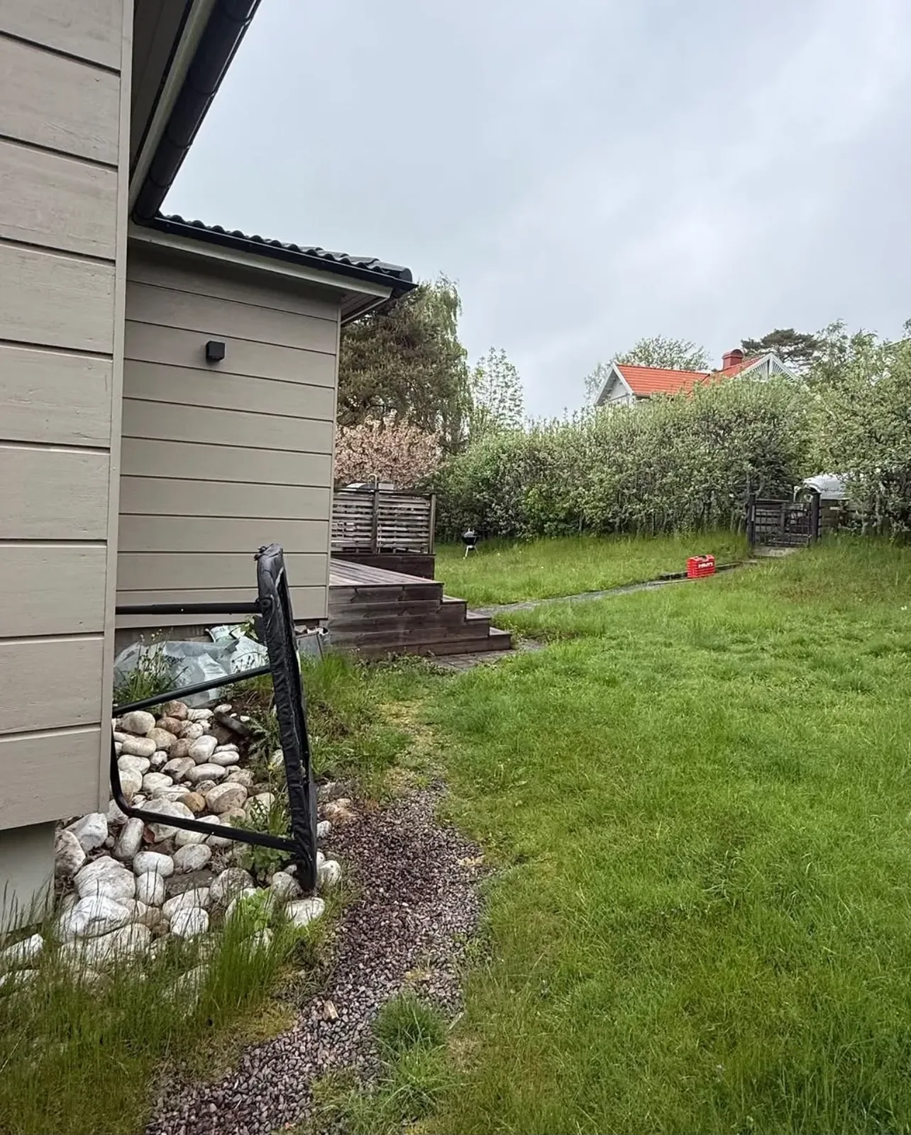 Gräsmatta och stenkant vid ett beige hus