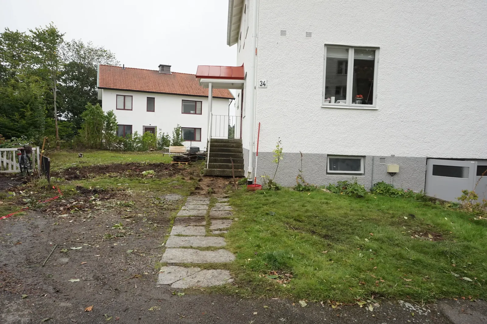 Grusig och ojämn yta vid husets gavel innan arbetet