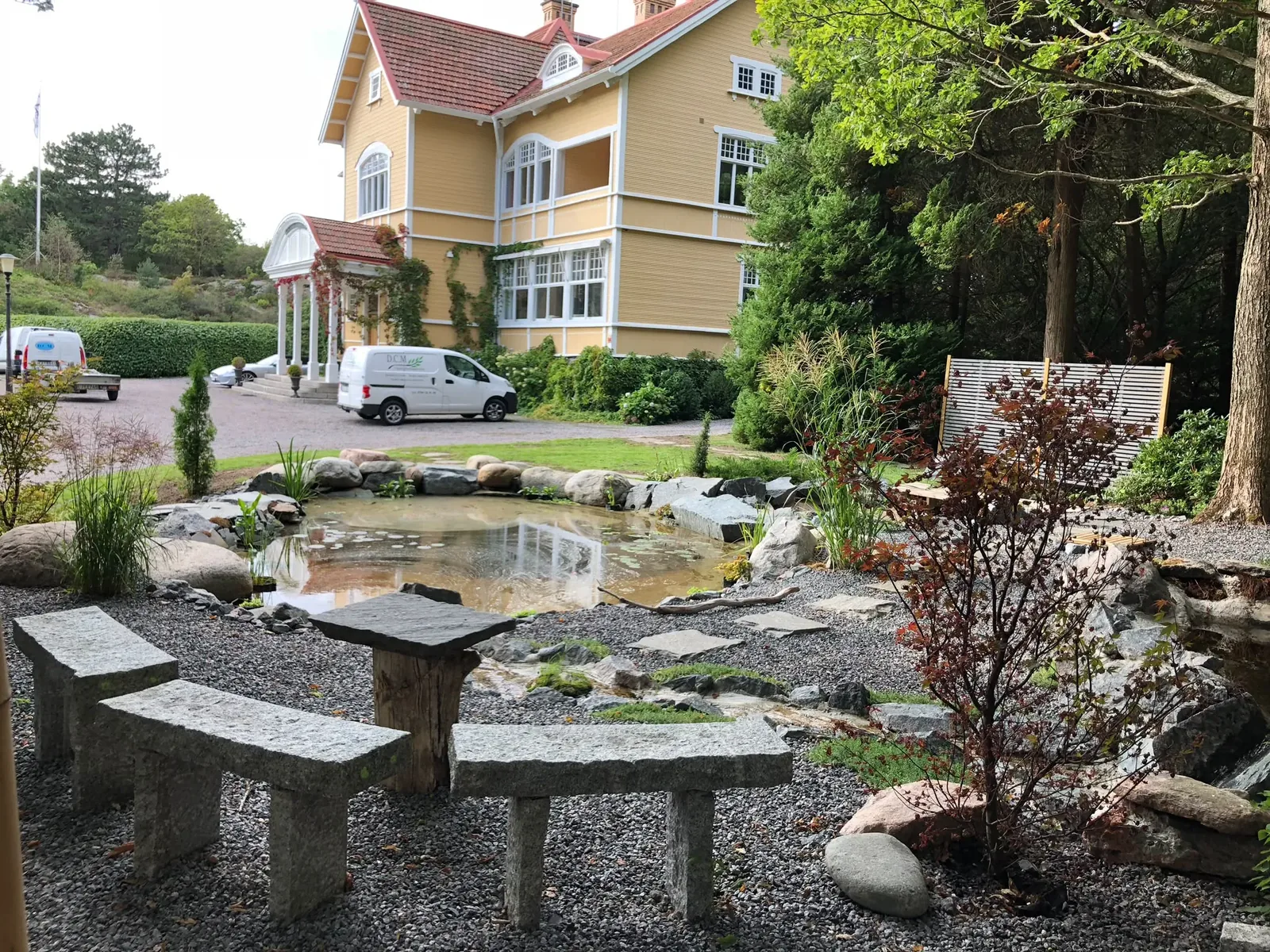 Färdig damm med stenbänkar och planteringar
