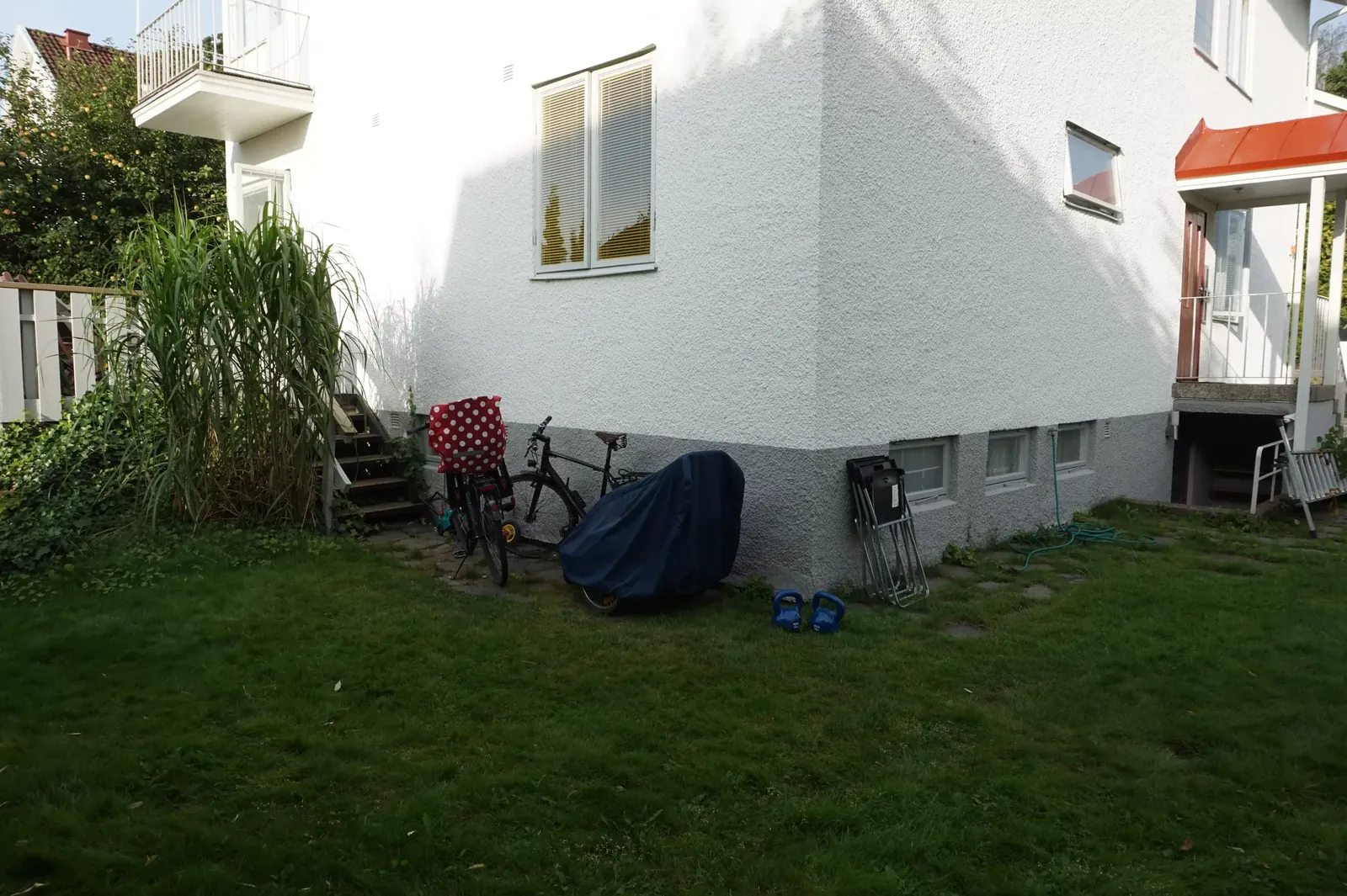 Gräs och cyklar längs husets sockel innan arbetet