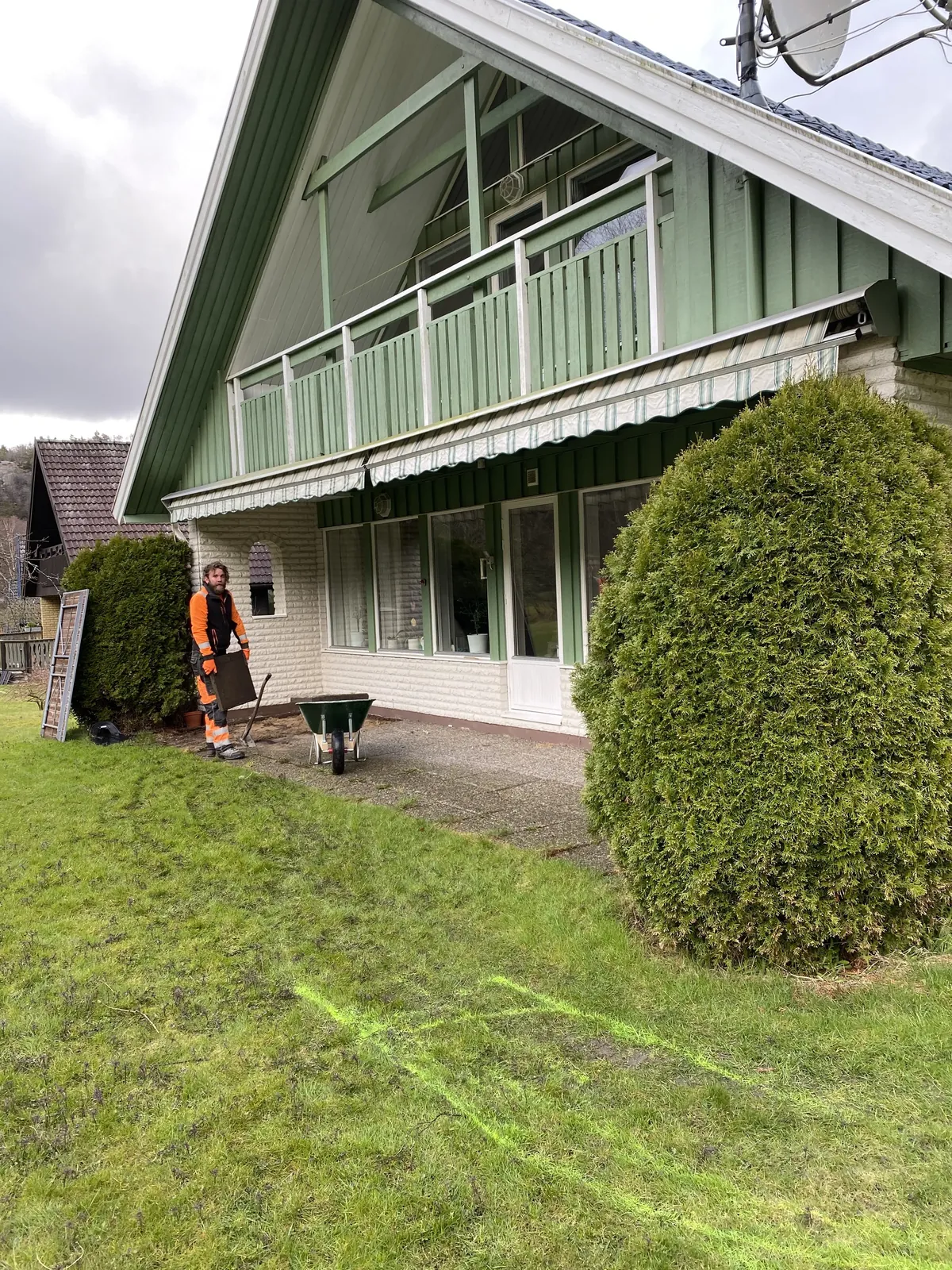 Gräsmatta vid ett hus med grön fasad innan stenläggningen