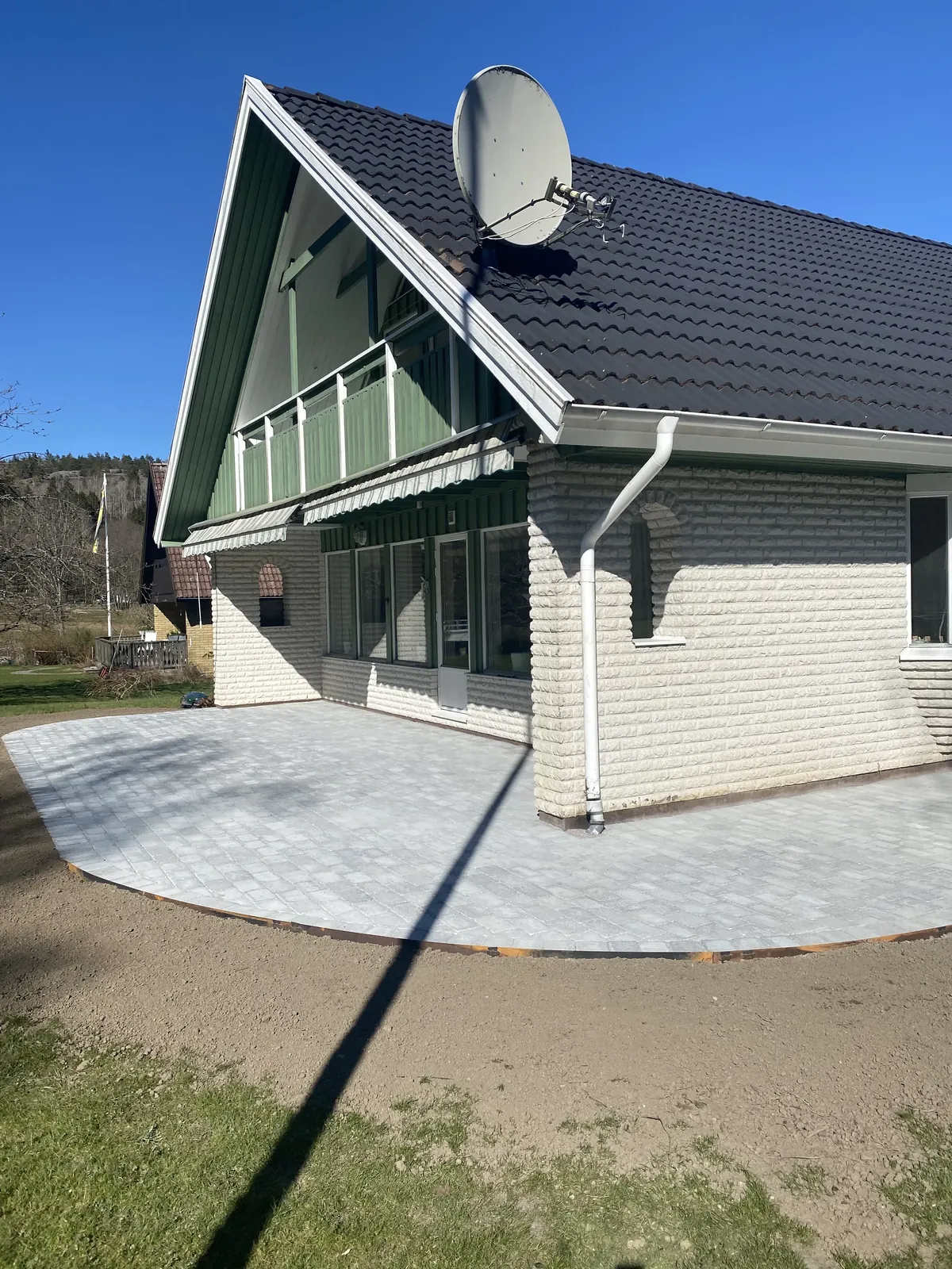 Ny rundad stenläggning vid ett hus med grön fasad