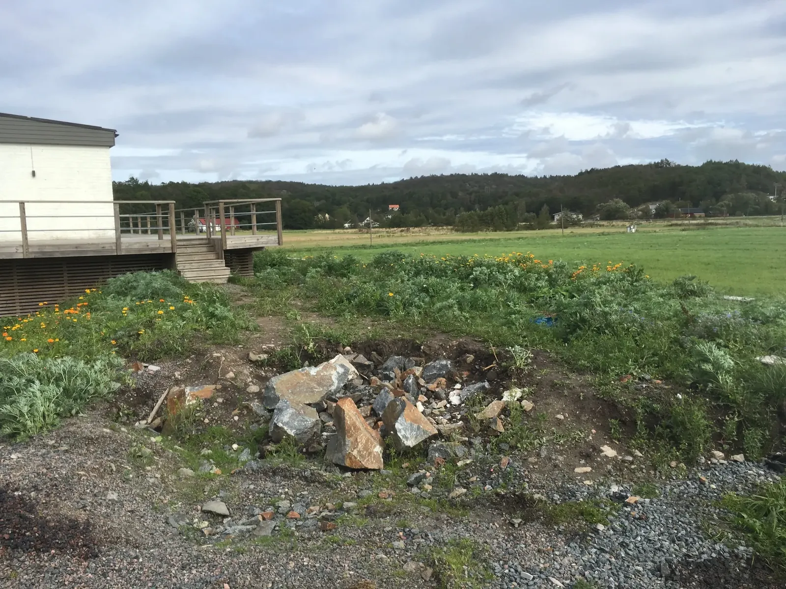 Ojämn yta med stenar framför ett hus på landet innan arbetet