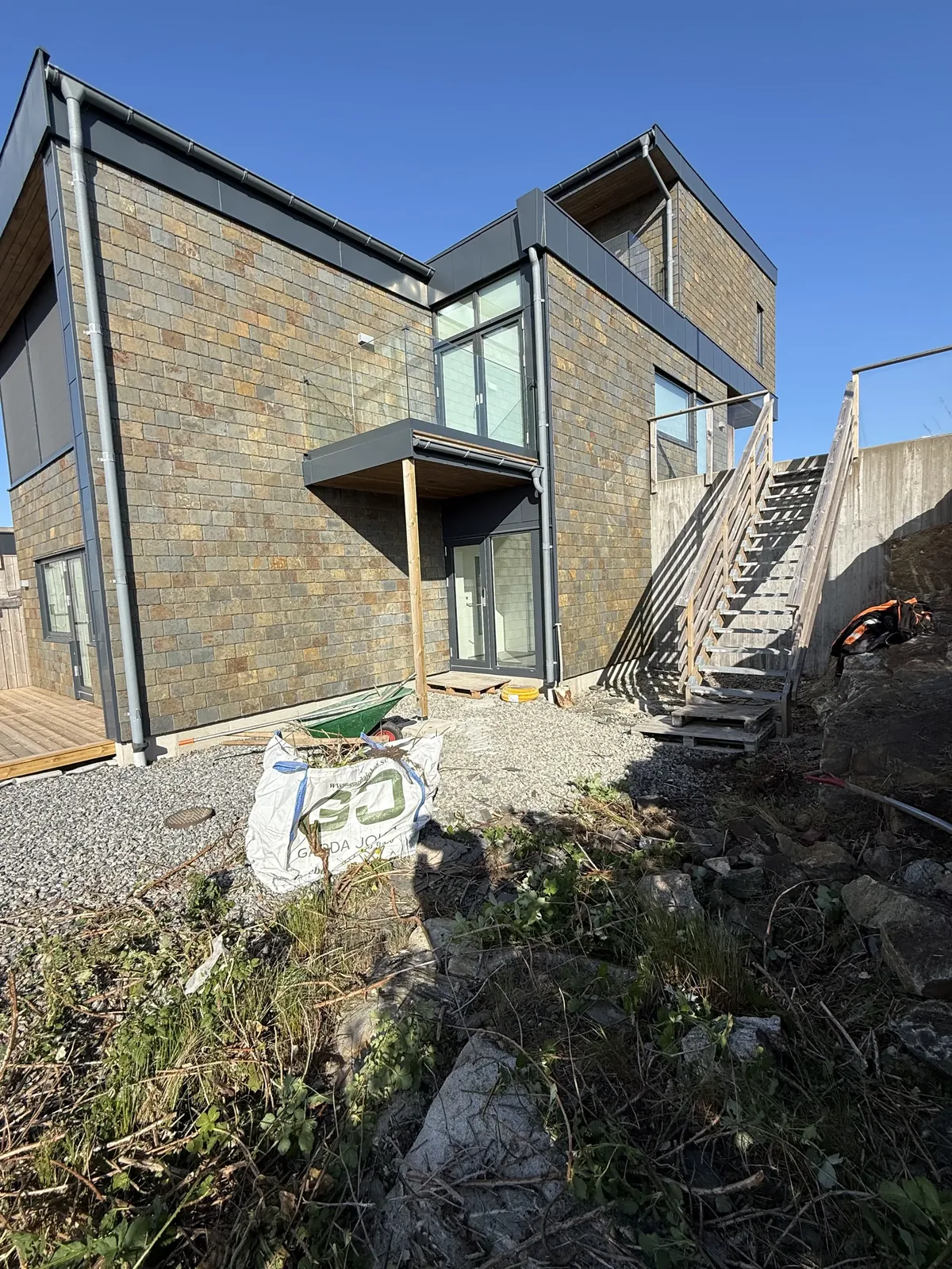 Modernt hus i natursten innan markarbetet