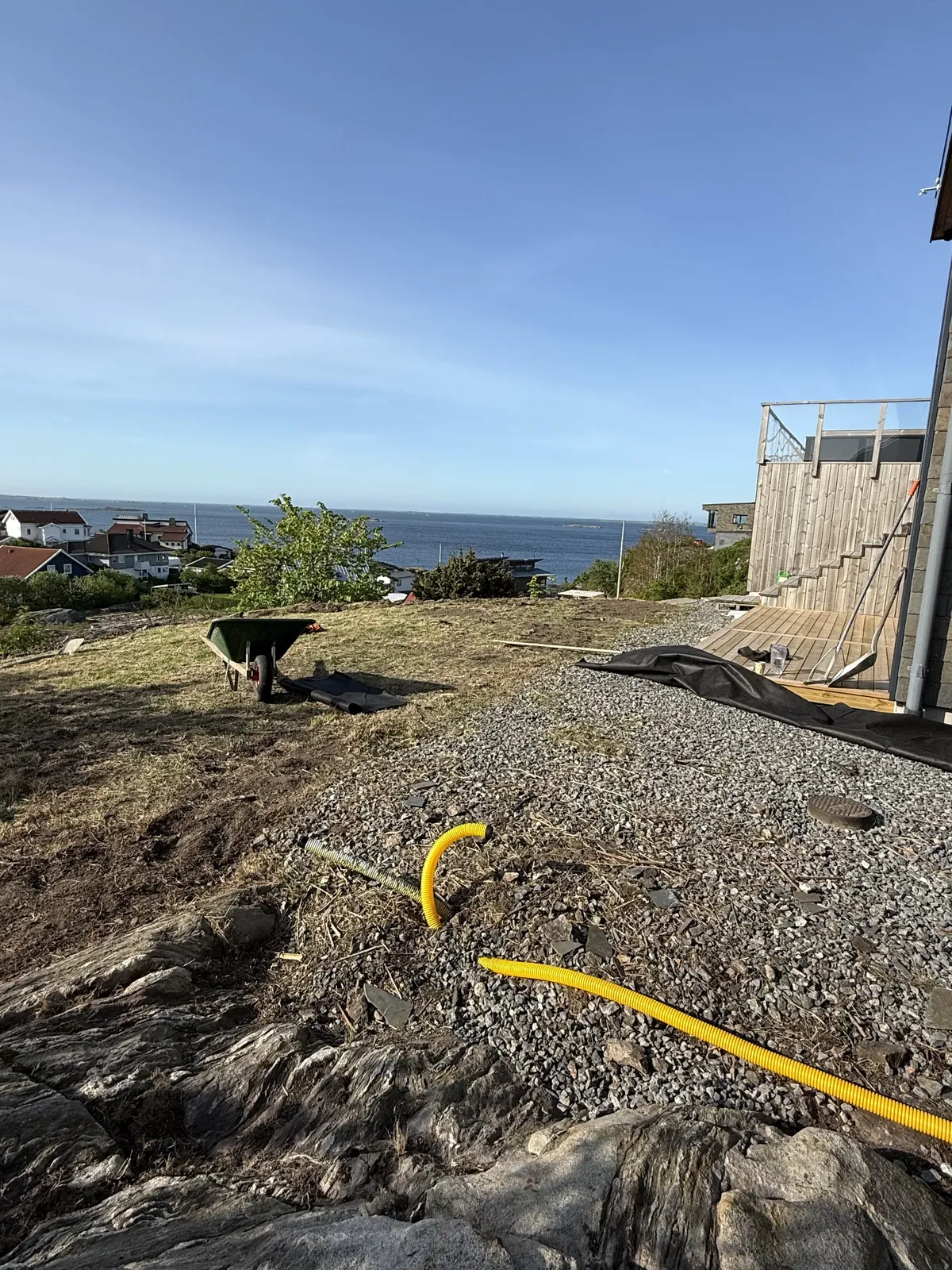 Grusyta och slang vid ett hus med havsutsikt under arbetet