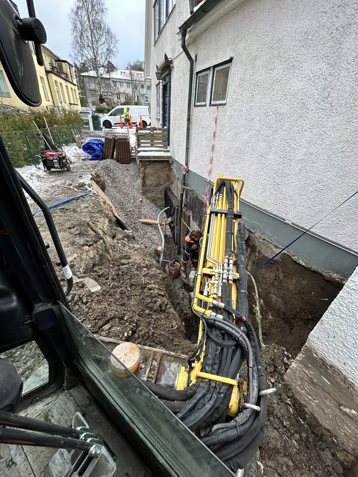 Grävmaskin vid husgrunden under dräneringsarbetet