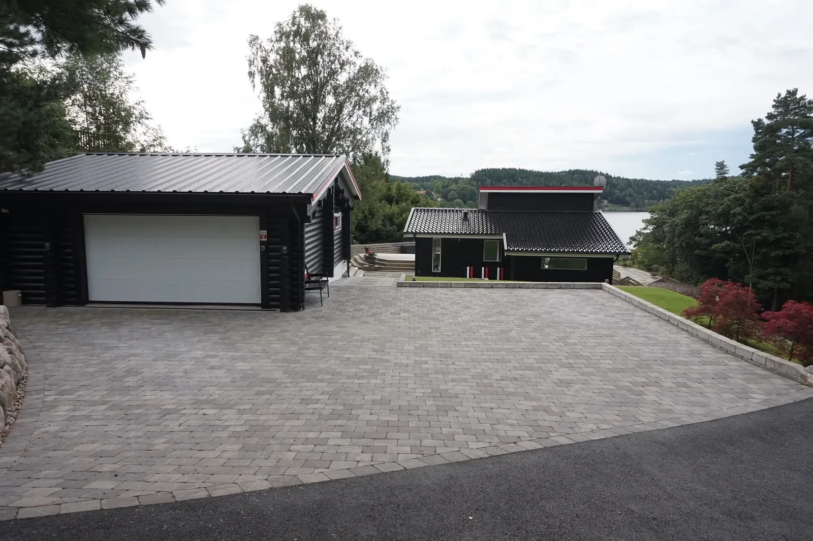 Ny stenlagd uppfart framför ett svart garage