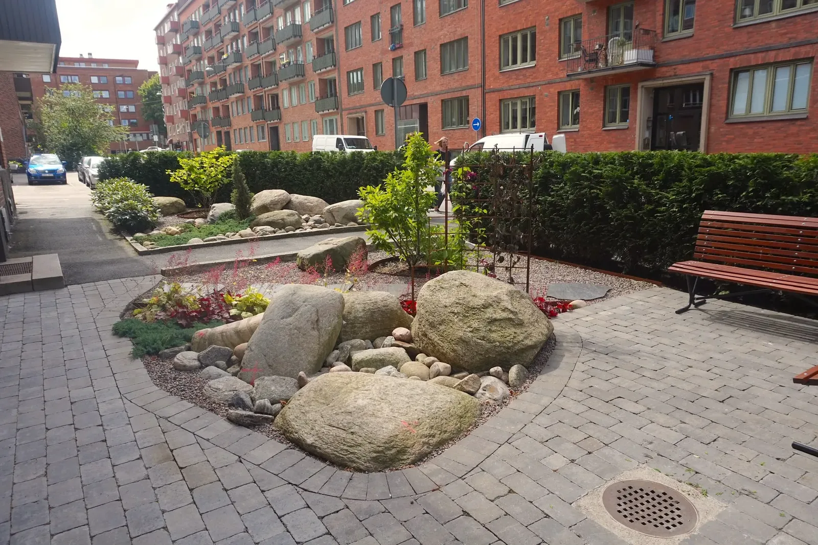 Rund plantering med stora stenar på en stenlagd innergård