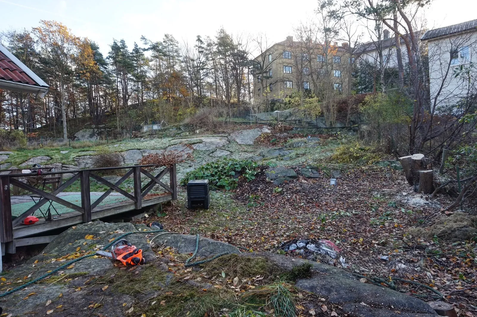Kuperad trädgård med berg och träräcke innan arbetet