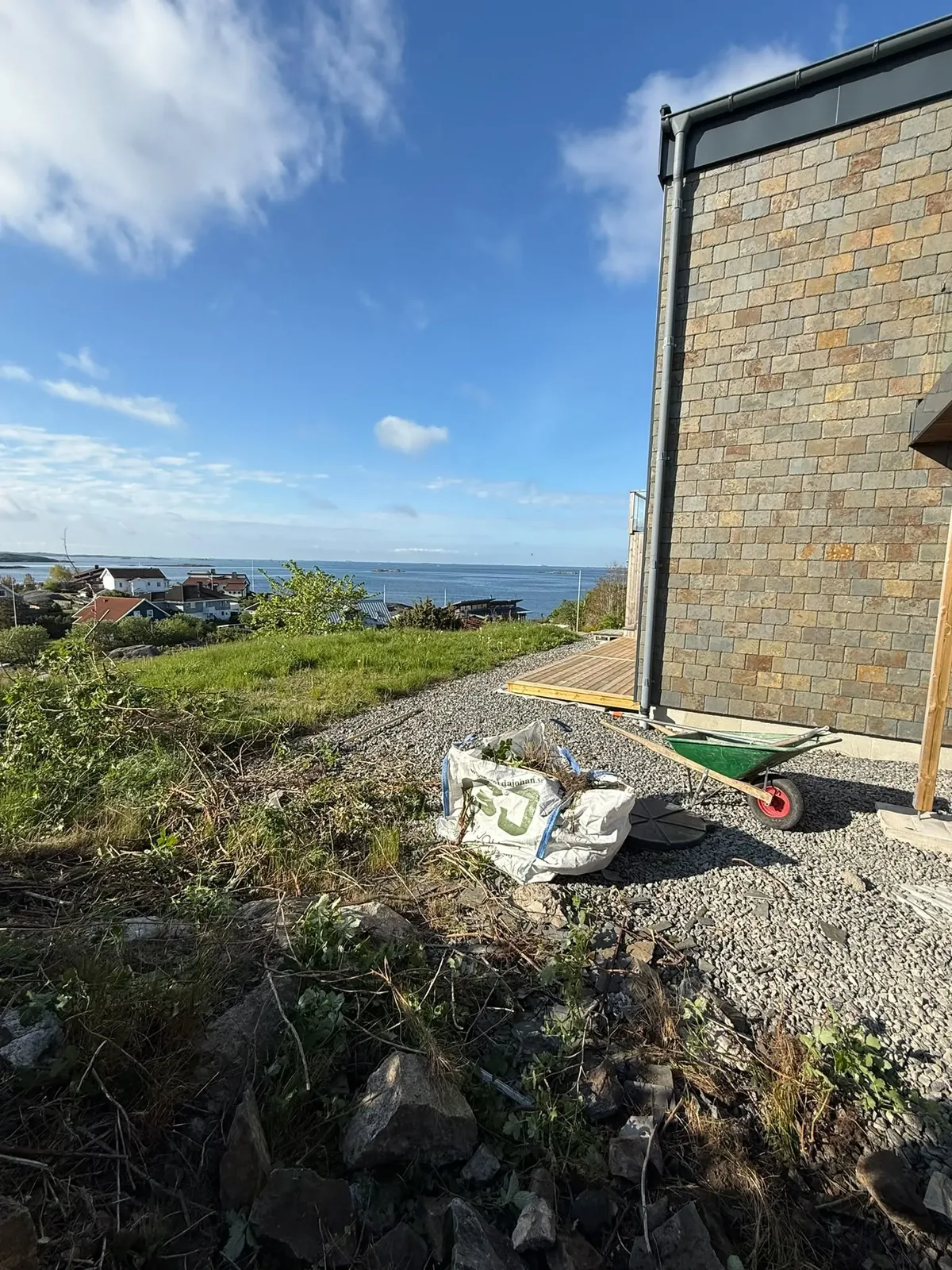Slänt med sly vid ett hus med havsutsikt innan arbetet